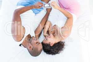 Happy husband and wife holding sonogram on bed