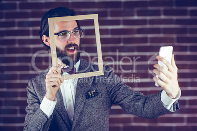 Handsome man taking selfie while holding frame