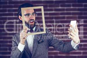 Handsome man taking selfie while holding frame