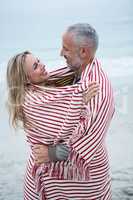 Couple embracing while wrapped in a beach towel