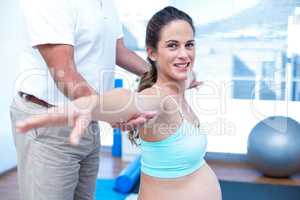 Portrait of pregnant woman stretching hands while exercising