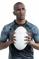 Thoughtful athlete holding rugby ball