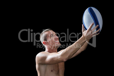 Smiling handsome shirtless sports player holding ball