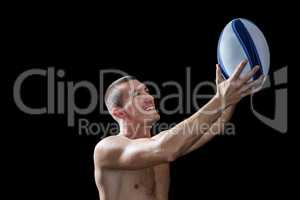 Smiling handsome shirtless sports player holding ball