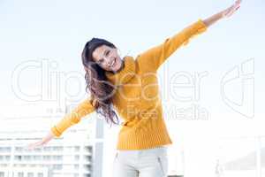 Happy woman looking camera with arms raised on