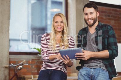 Portrait of smiling colleagues using tablet