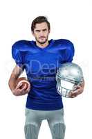 American football player holding helmet and ball