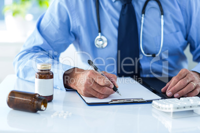 Cropped image of male doctor writing document in hospital