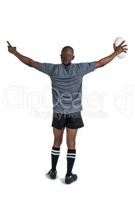 Rear view of athlete with arms raised holding rugby ball