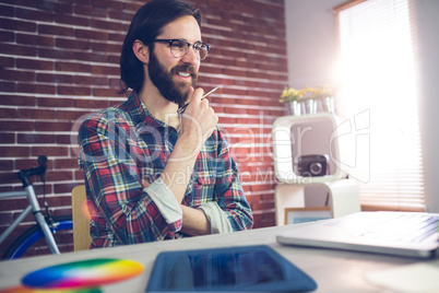 Smiling creative businessman with hand on chin