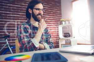 Smiling creative businessman with hand on chin