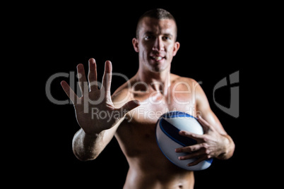 Confident shirtless sports player showing hand while holding bal