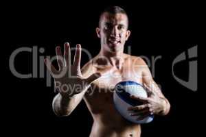 Confident shirtless sports player showing hand while holding bal