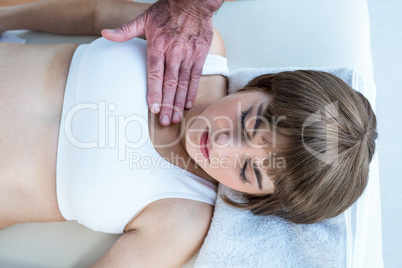 High angle view of therapist performing reiki over woman