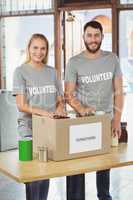 Happy man and woman separating donation stuffs in office