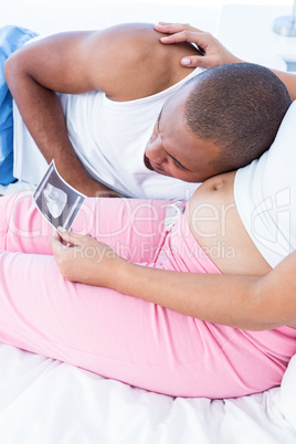 Pregnant wife showing sonogram to husband