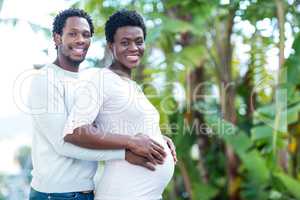 Portrait of happy man embracing wife while standing