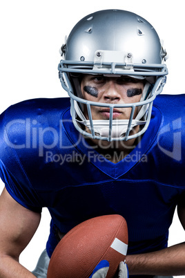 Determined American football player in uniform holding ball