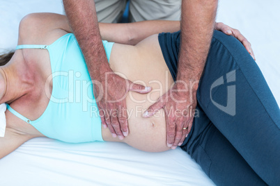 Trainer massaging pregnant woman at gym