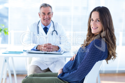 Portrait of pregnant woman with male doctor in clinic