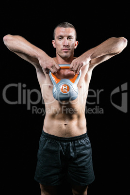 Confident shirtless athlete exercising with kettlebell