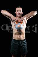 Confident shirtless athlete exercising with kettlebell