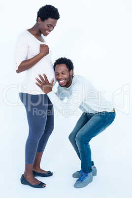 Happy man with closed eyes listening to his pregnant wife belly