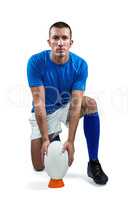 Full length portrait of rugby player placing ball