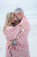 Couple embracing while wrapped in a beach towel