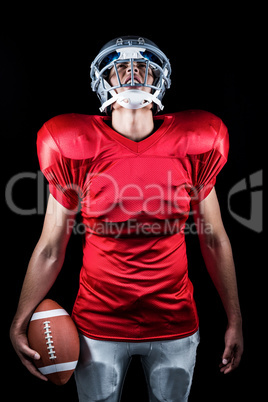 American football player holding ball while looking up