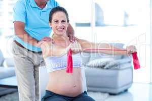 Portrait of smiling pregnant woman stretching exercise band