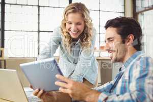 Colleagues using digital tablet in office