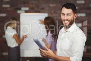 Portrait of smiling young businessman holding digital tablet