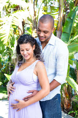 Smiling husband touching pregnant wife belly