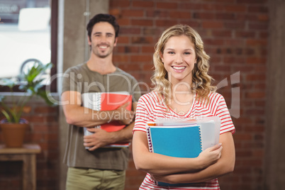 Portrait of smiling businesswoman holding files and folders in o