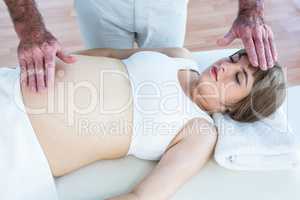 Pregnant woman getting reiki from male therapist