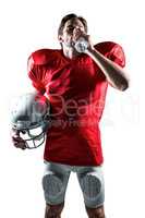 Thirsty sportsman in red jersey holding helmet while drinking wa