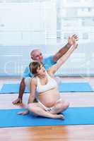 Male instructor teaching yoga to pregnant woman