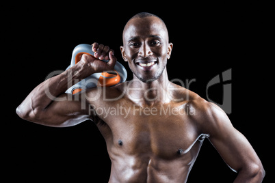 Portrait of muscular man smiling while holding kettlebell