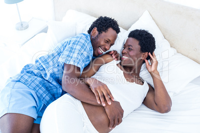 Husband and wife laughing while relaxing on bed