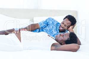 Delighted pregnant woman lying on bed with her husband