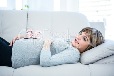 Pregnant woman with baby shoes on belly