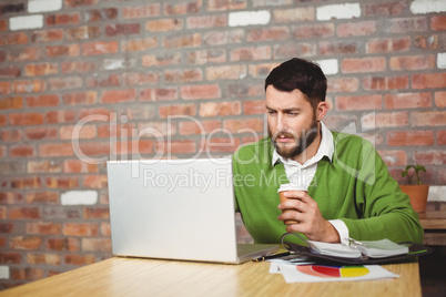 Businessman holding coffee while working in office