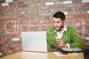 Businessman holding coffee while working in office