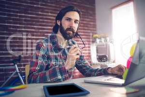 Portrait of thoughtful businessman using laptop