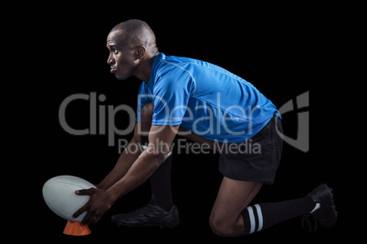 Confident rugby player looking away while keeping ball on kickin