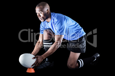 Rugby player looking away while keeping ball on kicking tee