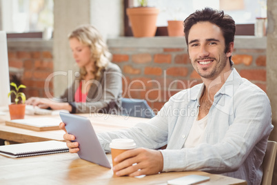 Portrait of smiling businessman holding digital tablet and coffe