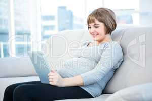 Smiling pregnant woman using digital tablet at home