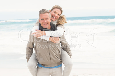 Smiling man giving woman a piggy back